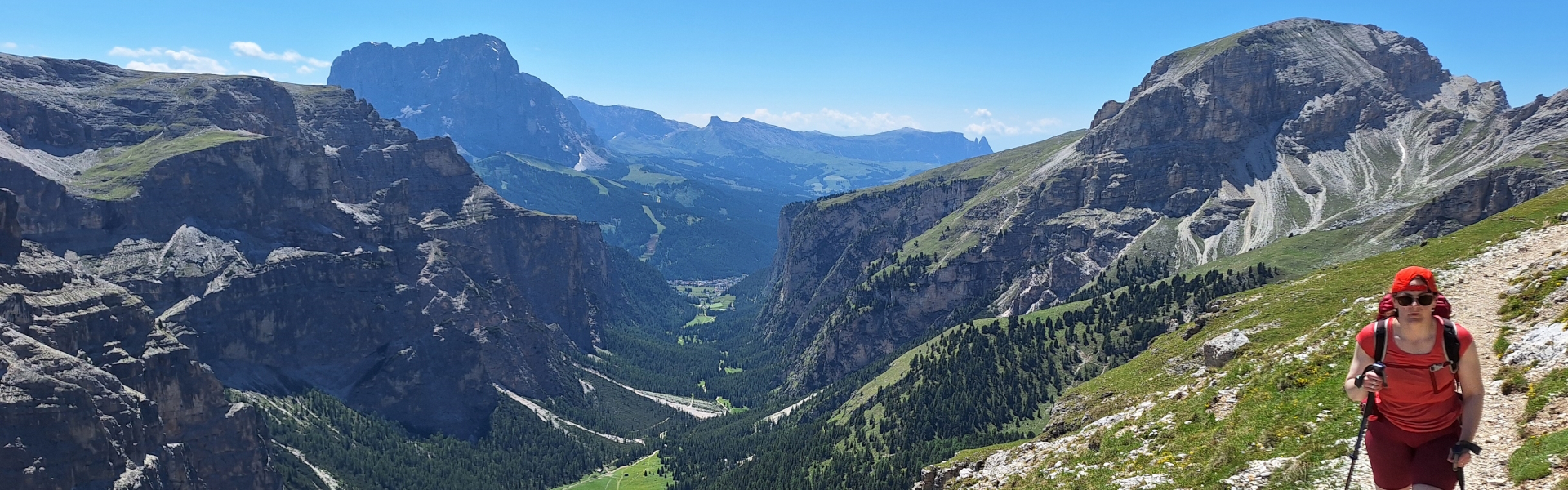 A hiker nearing Rifugio Puez, with the Sella pass behind, on the Alta Via 2