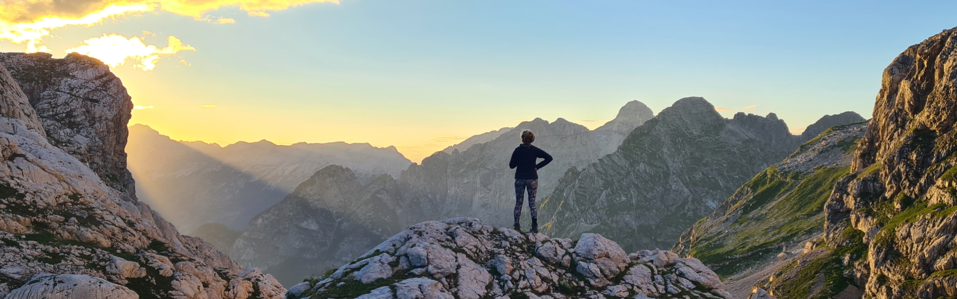 Hiker silhouetted by the sunset outside Koča na Doliču