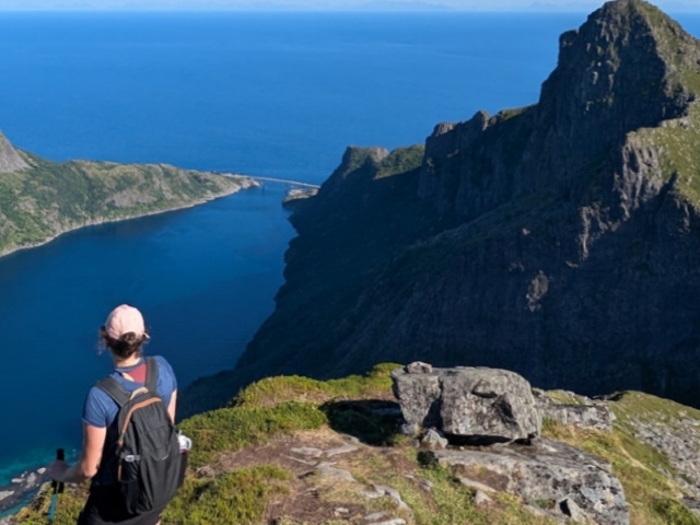 A walker on a peak in Lofoten, sea below